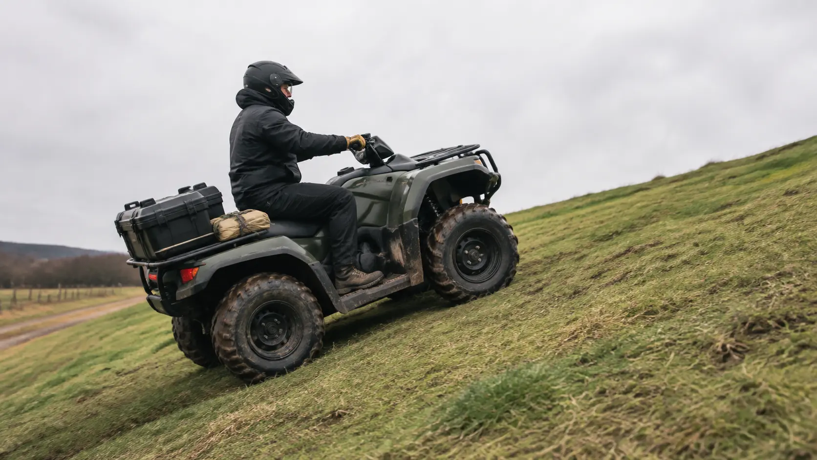 ATV utilitar generic urcând lent o pantă ierboasă cu rider echipat