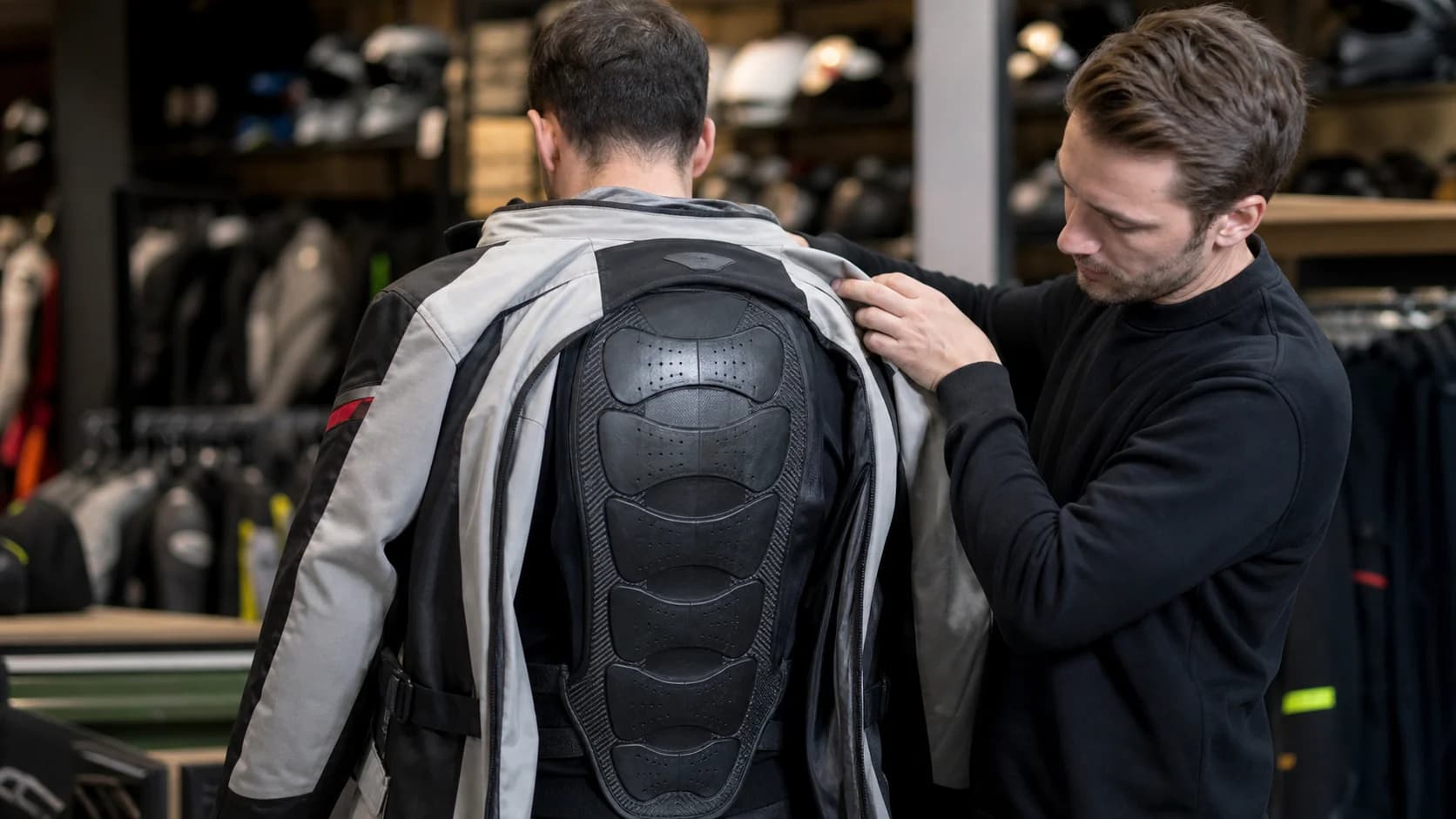Motociclist care probează o protecție de spate sub geaca moto într-un magazin de echipamente