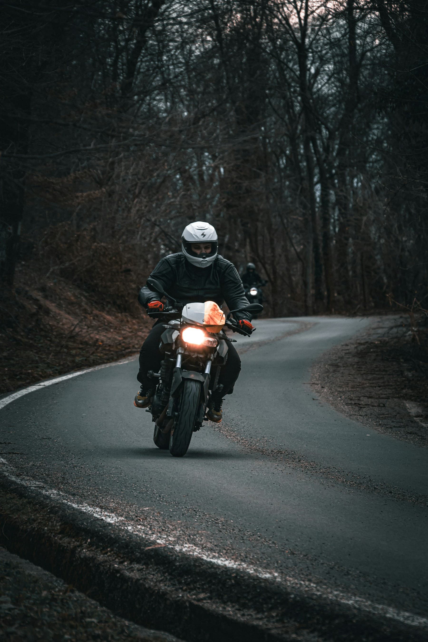Motociclist echipat pe un drum liniștit prin pădure