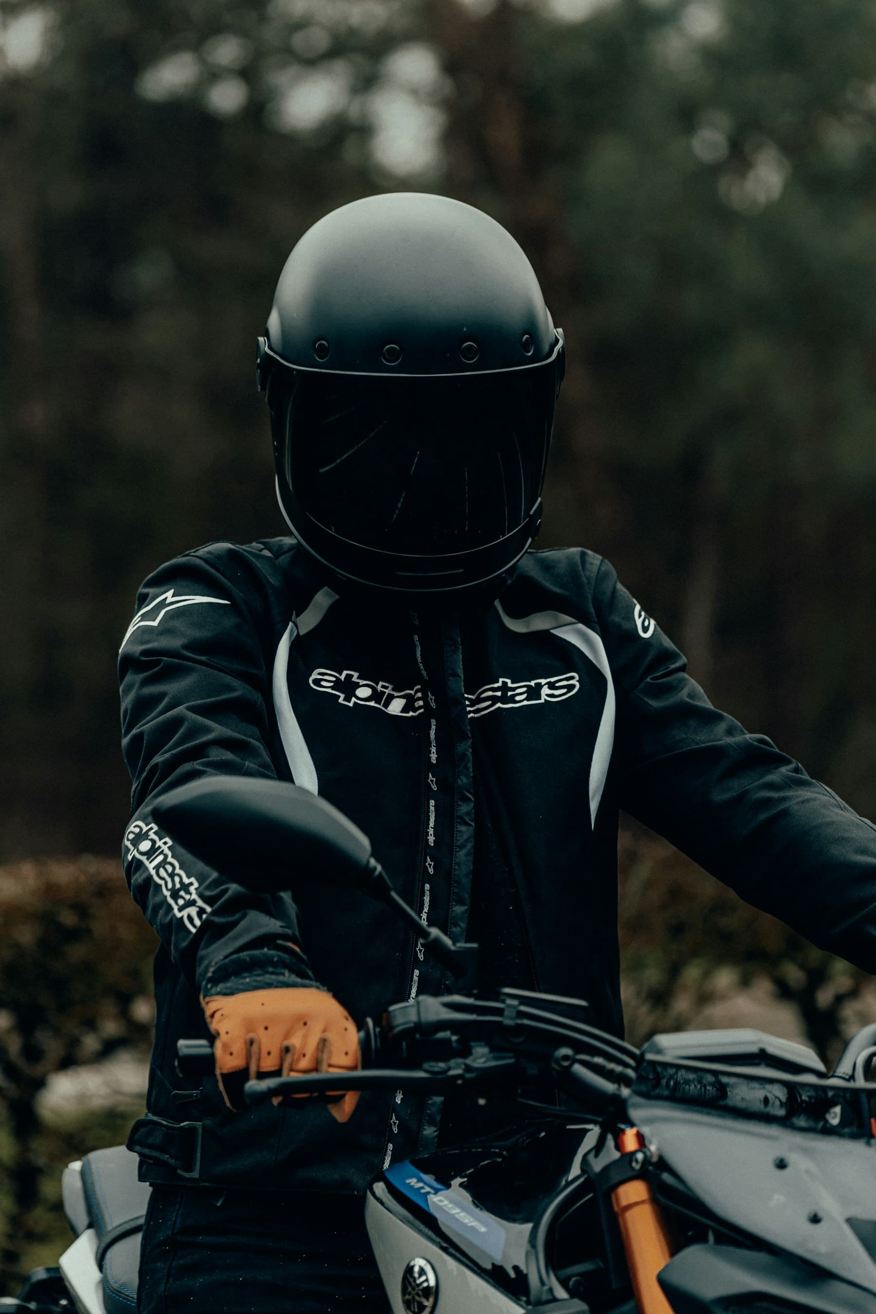 Motociclist pe o motocicletă naked într-o zonă împădurită